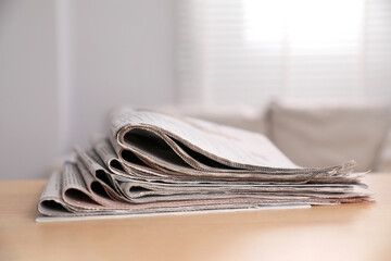 Stack of newspapers in different languages on table indoors