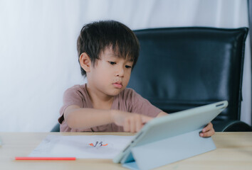 Naklejka premium Education.Cute asian child boy learning and drawing with the online teacher on tablet digital at home.