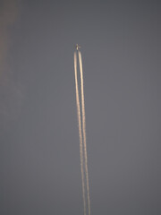 Jet Vapor Trails In Gray Sky Behind Distant Plane