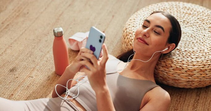 Woman, relax and smile with earphones, mobile phone or scroll in home for online yoga class on floor. Female person, technology and happy for connection, streaming or podcast on break or rest for zen