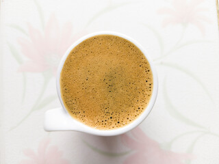 a cup of coffee made by moka pot with white floral tile background