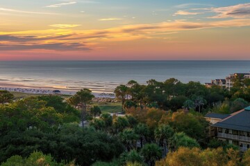 Obraz premium Oceanfront beach on Head Island, South Carolina. Coligny beach with hotels and trees in foreground at sunset. Drone captures serene landscape with blue water, sandy shore, and cloudy sky.