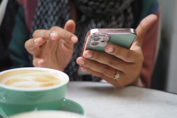 Closeup of a Woman Using a Smartphone at a Caf with a Cup of Coffee