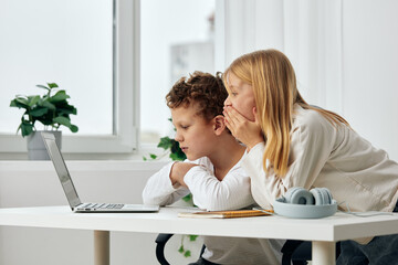 Happy children studying online with laptops at home, enjoying their elearning experience A boy and...