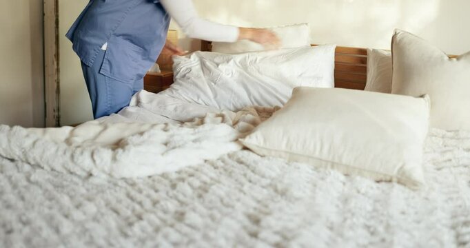 Nurse, person and cleaning bed for housekeeping in retirement home with change sheets and hygiene. Assisted living, caregiver and hands fix pillows in bedroom for maintenance, assistance or housework