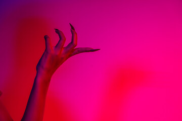 A terrifying witch's hand with long red nails, resembling a demon or vampire. Its gnarled appearance hints at monstrous origins, resembling an alien or ghostly entity,with zombie-like decayed skin.