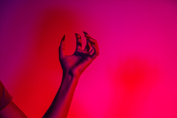 A terrifying witch's hand with long red nails, resembling a demon or vampire. Its gnarled appearance hints at monstrous origins, resembling an alien or ghostly entity,with zombie-like decayed skin.