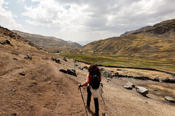 Turista caminando y haciendo senderismo por una ruta en el nevado de Ausangate en la Cordillera de...