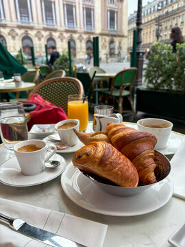 Pain au chocolate and croissant on table with coffee at the terrace with city view, elegant breakfast concept.  