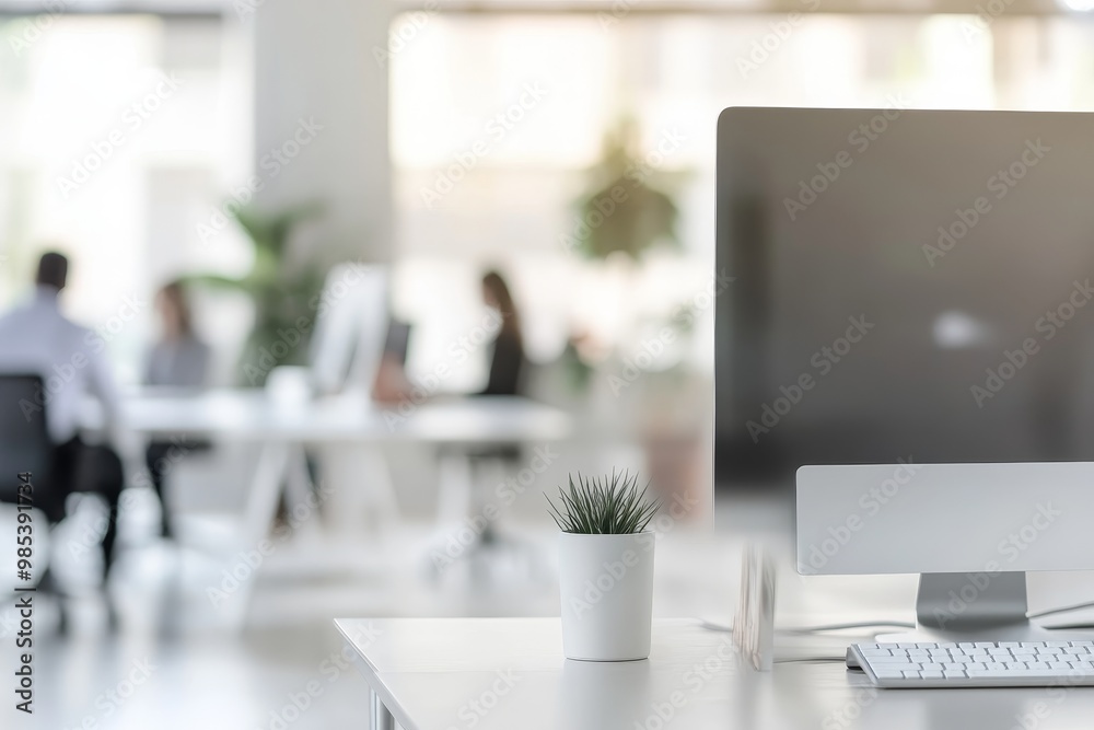 Poster close up of a white desk in a modern office with a computer and a plant.