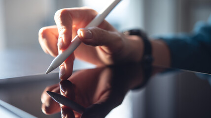 Closeup, woman hand with stylus pen using digital tablet, finger touching on tablet screen with...