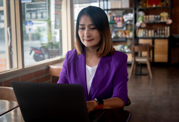 Businesswoman sitting in the cafe using laptop working account report finance, coffee break time freelance lifestyle  concept 