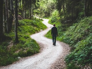 Fototapeta premium A person walks along a winding path through a lush forest, surrounded by greenery and trees, evoking a sense of tranquility and exploration.