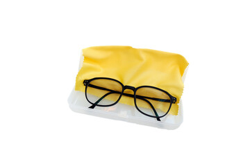 a pair of black-rimmed glasses, resting on a yellow microfiber cloth, tucked neatly inside a clear...