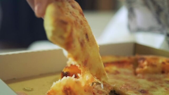 Close up of fresh pizza from fast food restaurant delivered in a box to young hangry woman happily chewing sitting on sofa in her living room.