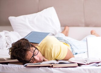 Young student studying in bed for exams