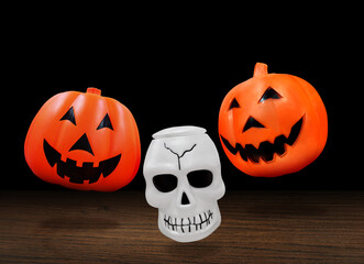 Plastic pumpkin head, plastic skull, Halloween symbol isolated on black background.
