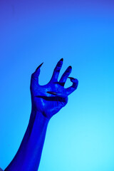 A blue witch hand with sharp red nails, set against a backdrop of blue fire. This eerie figure embodies demonic, ghostly, and zombie elements, perfect for Halloween horror and fantasy settings.