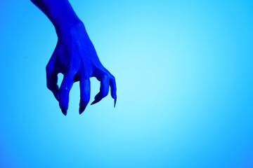 A blue witch hand with sharp red nails, set against a backdrop of blue fire. This eerie figure embodies demonic, ghostly, and zombie elements, perfect for Halloween horror and fantasy settings.