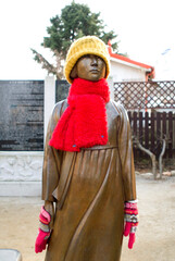 Gunsan-si, Jeollabuk-do, South Korea - May 17, 2018: Peace Girl Statue with fur gloves, hat and scarf in winter at Dongguksa Temple