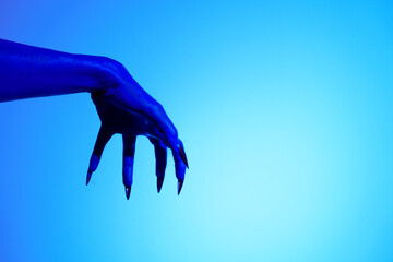 A blue witch hand with sharp red nails, set against a backdrop of blue fire. This eerie figure embodies demonic, ghostly, and zombie elements, perfect for Halloween horror and fantasy settings.