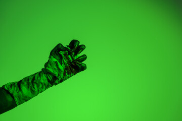 A bloodied witch hand wrapped in bandages, set against a green fire background. This demonic hand...