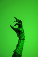 A bloodied witch hand wrapped in bandages, set against a green fire background. This demonic hand...