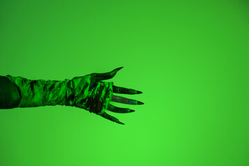 A bloodied witch hand wrapped in bandages, set against a green fire background. This demonic hand...
