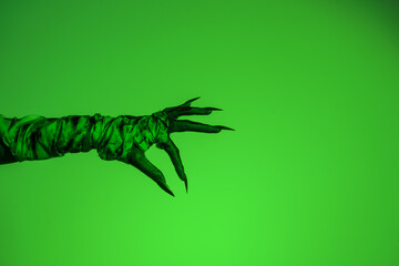 A bloodied witch hand wrapped in bandages, set against a green fire background. This demonic hand...