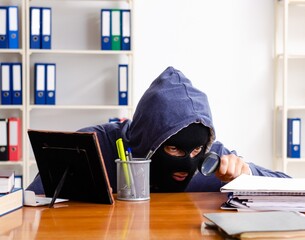 Male thief in balaclava in the office