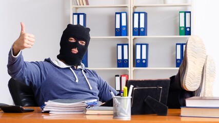 Male thief in balaclava in the office