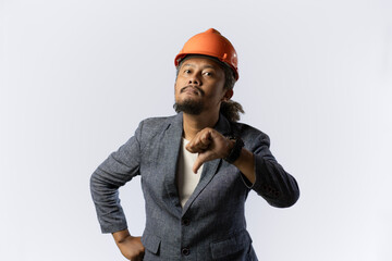 the project leader makes a gesture of dissatisfaction or disbelief by giving a thumbs dostylish asian man with orange suit and helmet on white background. construction or mining business concept photo