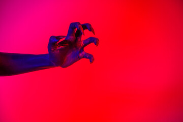 A witch hand with long nails appears against a red fire background, evoking a demonic, monstrous presence. Blending vampire, alien, ghost, and zombie elements, it perfectly embodies Halloween