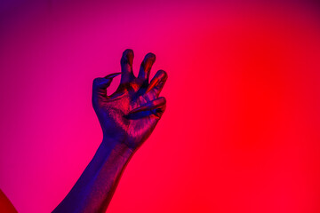 A witch hand with long nails appears against a red fire background, evoking a demonic, monstrous presence. Blending vampire, alien, ghost, and zombie elements, it perfectly embodies Halloween