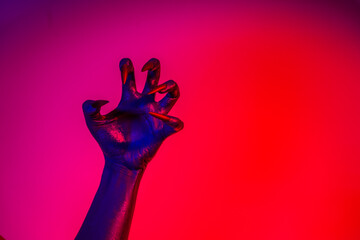 A witch hand with long nails appears against a red fire background, evoking a demonic, monstrous presence. Blending vampire, alien, ghost, and zombie elements, it perfectly embodies Halloween
