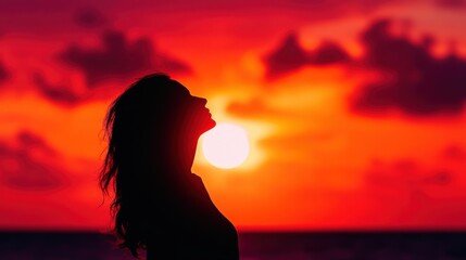 Fototapeta premium A silhouetted profile of a woman against a stunning sunset, capturing the essence of tranquility and reflection in nature.