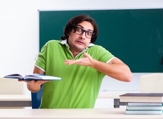 Young male student in front of green board