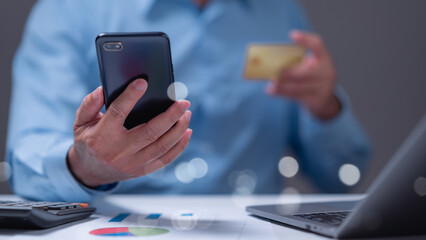 Person engages in online shopping using smartphone and credit card, surrounded by financial documents, highlighting convenience of digital transactions in todays fast-paced world