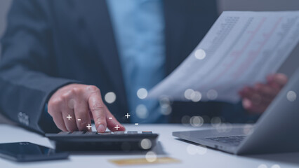 Business professional analyzes data using calculator while reviewing financial reports,...