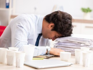 Obraz premium Young employee addicted to coffee