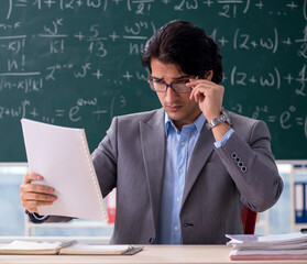 Young handsome math teacher in classroom