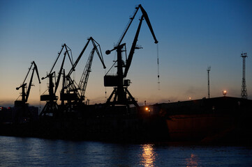 silhouette of port cranes at night.