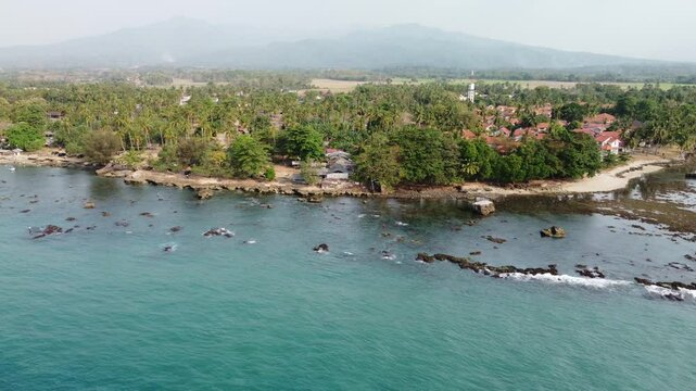 Aerial drone view of paradise beach Anyer, Indonesia. The waters are turquoise. Resort and mountain background.