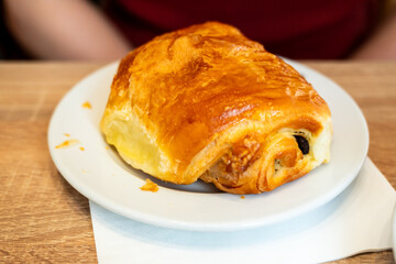 chocolate croissant on a plate in a a bakery - traditional french breakfast in Paris, France