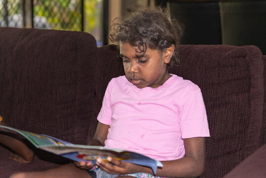 Aboriginal girl reading a book focus behind subject