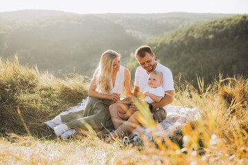 Happy Family Having a Picnic in a Scenic Meadow with Sunlit Hills in the Background © anatoliycherkas