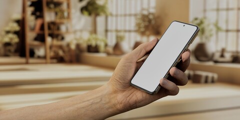 Caucasian White male using smartphone with a blank white screen. Studio, yoga, sunlight apps mockup. Vertical phone orientation