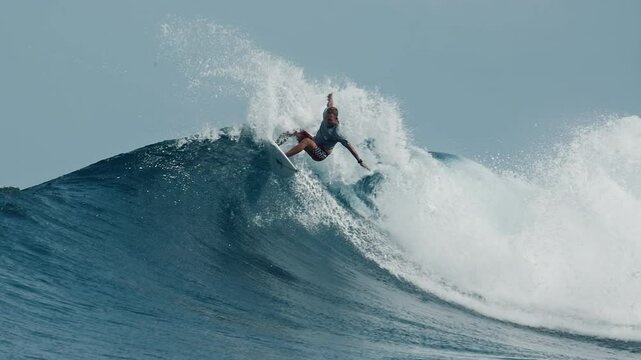 Surfer rides ocean wave in the Maldives, footage has speed warp effect with slow motion