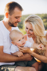 Happy Family Moment Outdoors with Parents and Baby Enjoying Sunny Day Together
