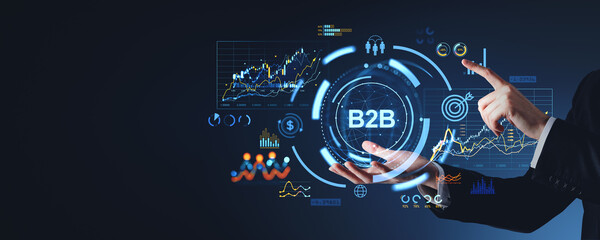 Businessperson interacting with a B2B digital interface, surrounded by futuristic graphs and icons. Dark background. Concept of business, technology, and networking
